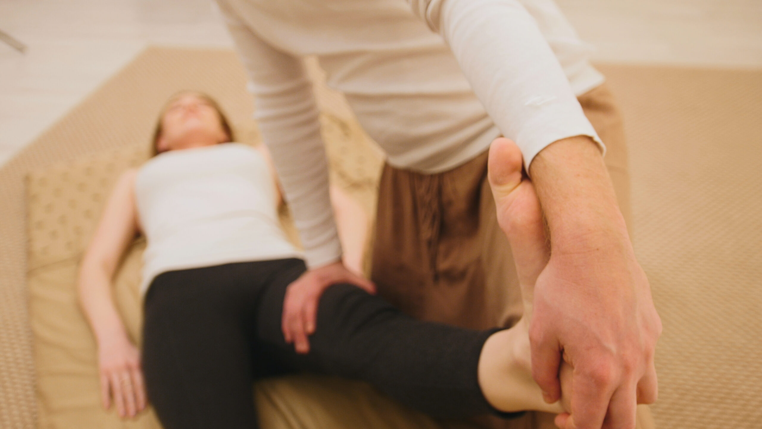 Male masseur holds the thai massage session - stretching of the legs and foots